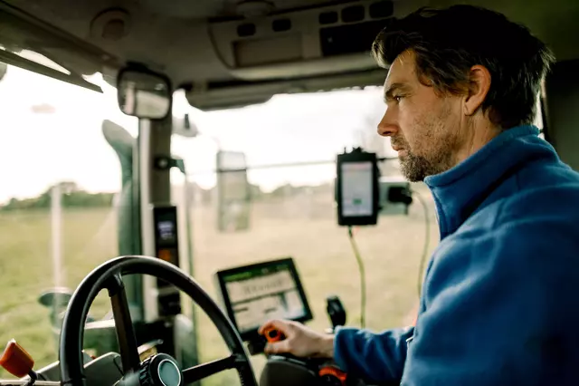 Ein Traktorfahrer bei der Arbeit in der Fahrerkabine.