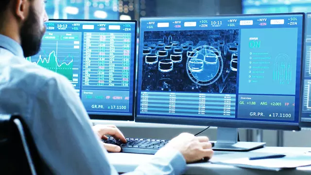 a business man working on a two displays computer to control a plant 
